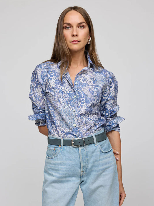 A person with long hair wears the Hinson Wu Margot Long Sleeve Lace Print in Blue/Ecru shirt, light blue jeans, and a grey belt, standing against a plain background.