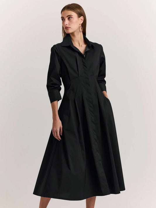 Woman wearing the Hinson Wu Martina 3/4 Sleeve Dress in Black, a collared midi dress with a fitted waist and flared skirt, crafted from stretch polished cotton, standing against a plain light background.