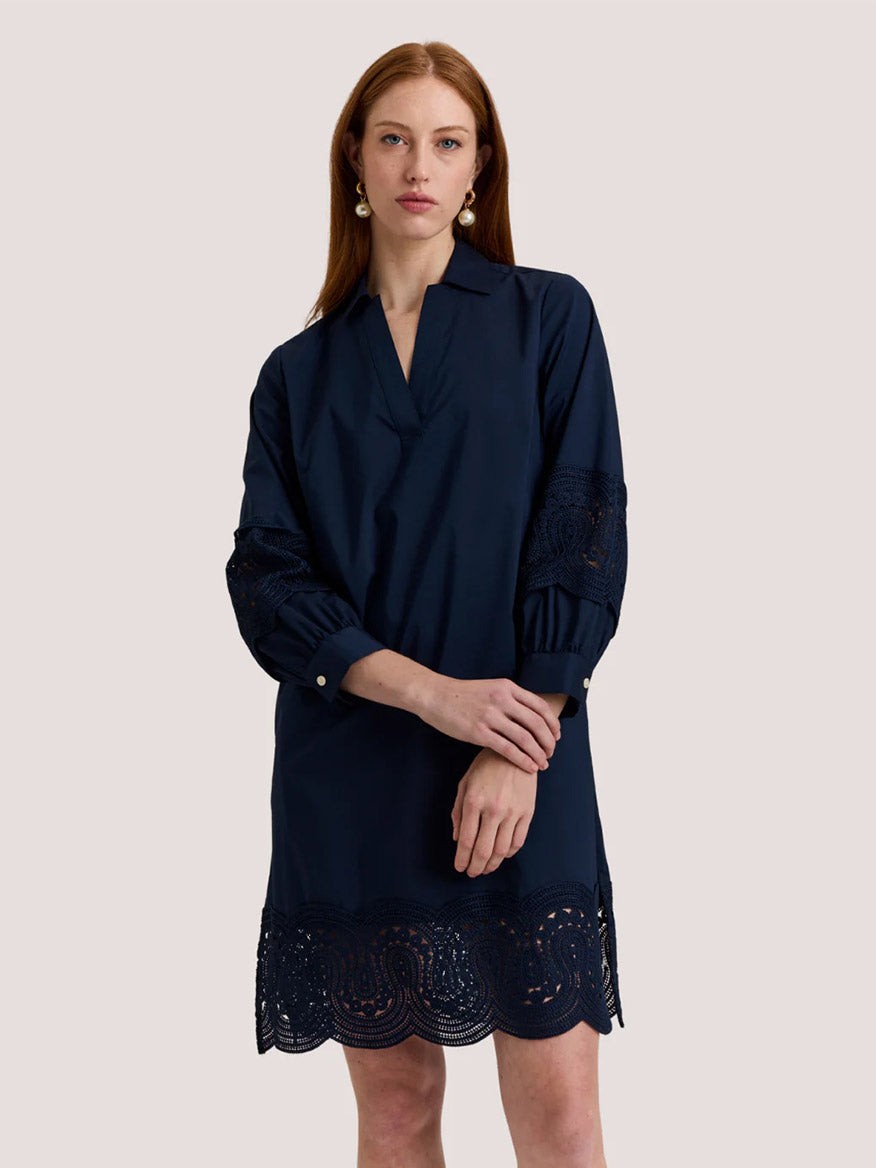 A woman stands against a plain light background wearing the Hinson Wu Mona Bracelet Sleeve Lace Dress in Navy, featuring stretch polished cotton and lace details on the sleeves and hem.