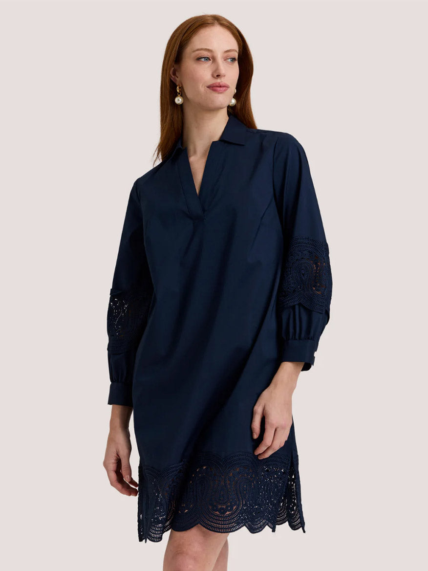 A woman wears the Hinson Wu Mona Bracelet Sleeve Lace Dress in Navy, a knee-length shift with lace-trimmed sleeves and hem, crafted from stretch polished cotton, standing against a plain light background.