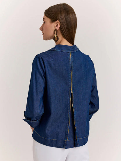 A woman stands facing away, wearing the Hinson Wu New Xena 3/4 Sleeve Denim Shirt in dark denim and white pants.