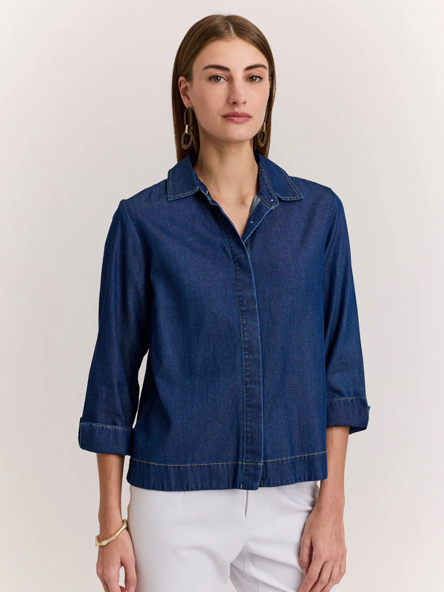 A woman stands facing forward, wearing the Hinson Wu New Xena 3/4 Sleeve Denim Shirt in Dark Denim and light-colored pants against a plain background.