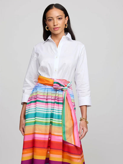 A woman wearing the Hinson Wu Robin 3/4 Sleeve Stripe Dress in White Ombre, featuring a colorful striped skirt and a bow, stands against a plain backdrop.