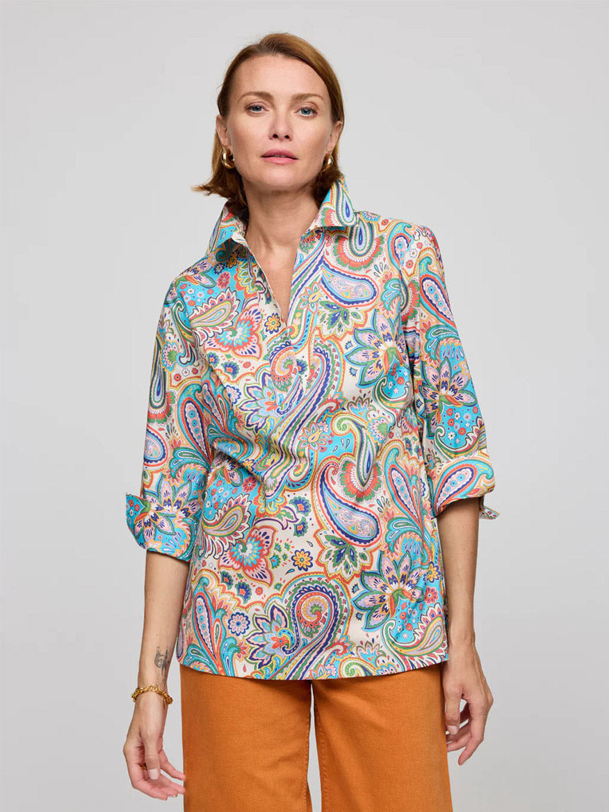 A person stylishly wears the Hinson Wu Vicky 3/4 Sleeve Multi Color Paisley Print Top with orange pants, standing against a plain background.