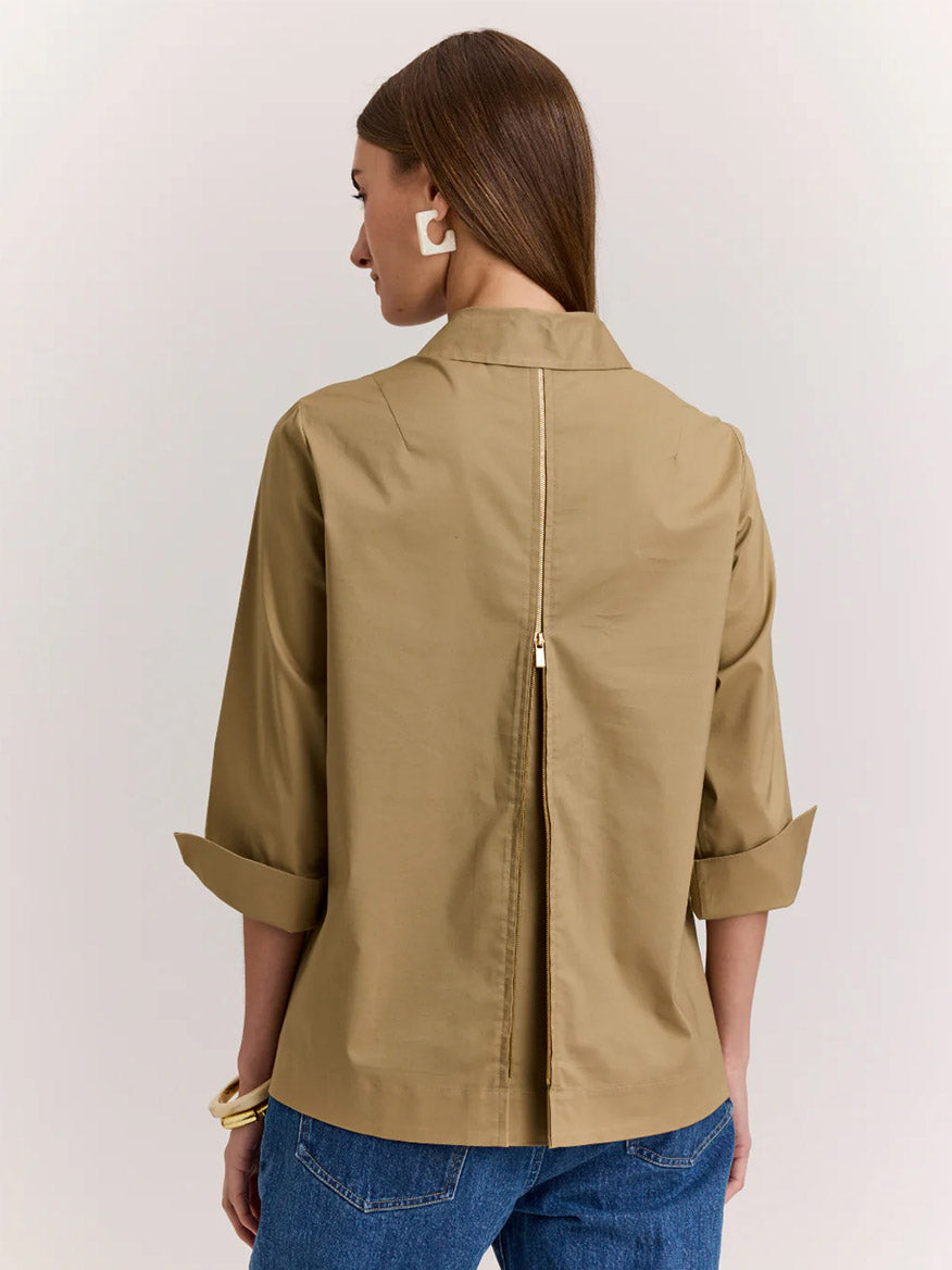 Woman stands with her back to the camera, wearing a Hinson Wu Xena 3/4 Sleeve Zip Back Shirt in khaki and blue jeans. The shirt features stretch polished cotton fabric and a visible vertical zipper down the back.