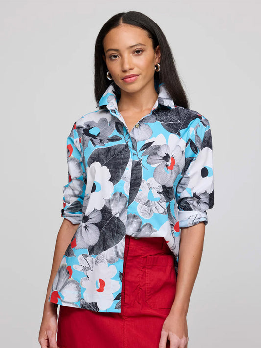 A woman with long dark hair wears the Hinson Wu Xena 3/4 Sleeve Pop Art Flower Shirt featuring blue, white, and black floral prints on refined cotton with rolled sleeves, paired with a red skirt against a plain light background.