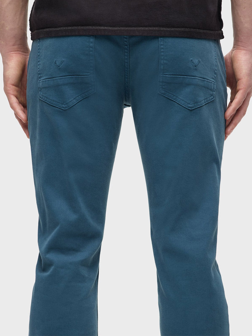 A person is wearing Hudson Blake Slim Straight Jeans in Deep Dive, which are showcased from behind, featuring a modern fit with a tapered leg and back pockets.