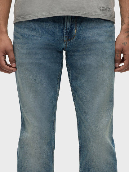 A person wearing Hudson Blake Slim Straight Jeans in Blue Cove, made with comfort stretch denim, paired with a gray waist-cropped shirt.