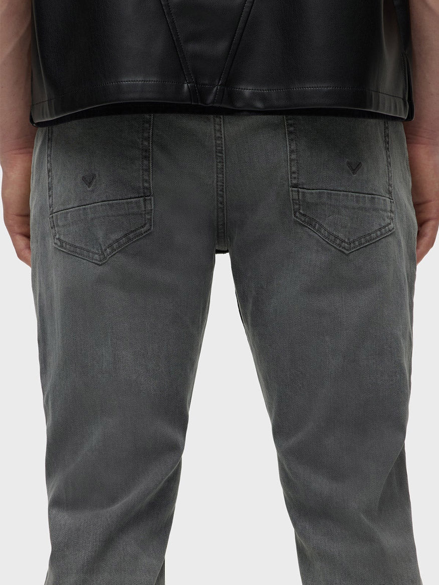 A person wearing a black leather jacket and Hudson Blake Slim Straight Jeans in Moon Ridge is shown from the back.