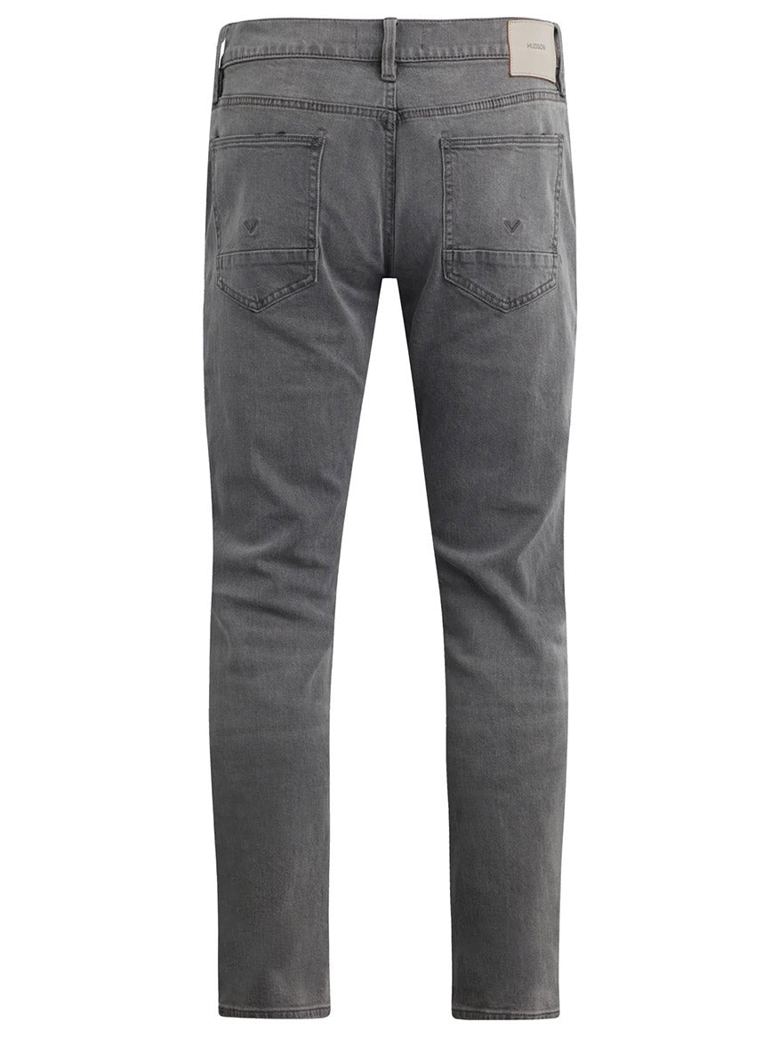 The Hudson Blake Slim Straight Jeans in Moon Ridge showcase a back view of mid-rise, grey denim with tapered legs, featuring two back pockets and a brown label on the waistband. These stylish jeans in the distinctive Moon Ridge wash add a unique touch to your wardrobe.