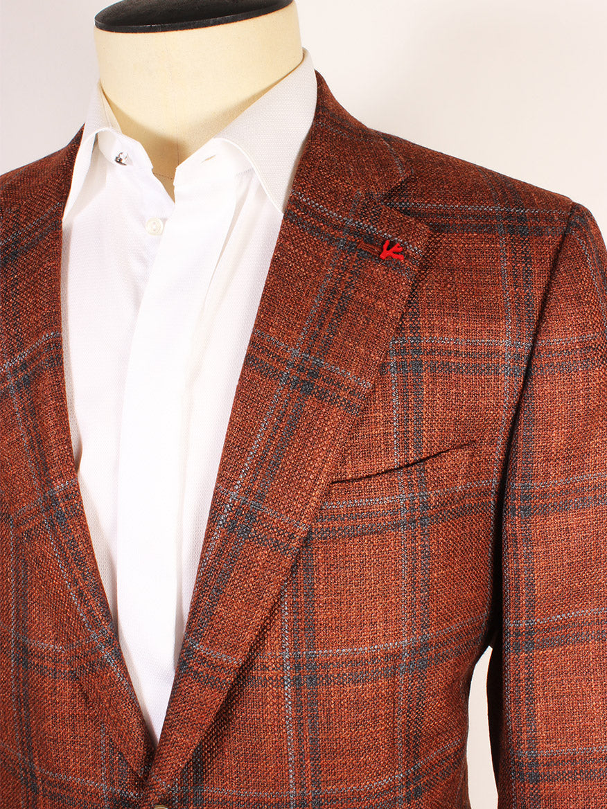 Close-up of a mannequin dressed in a white dress shirt and an orange plaid Isaia Matte Effect Sport Jacket in Rust with Navy & Grey Windows with a red lapel pin, showcasing the exquisite craftsmanship Made in Italy. The blazer features a refined matte effect that adds sophistication to its texture.