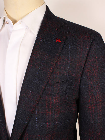 A close-up of a person wearing the Isaia Sanita Patch Pocket Sport Jacket in Navy with a white dress shirt and visible red lapel pin, highlighting the refined Italian craftsmanship.