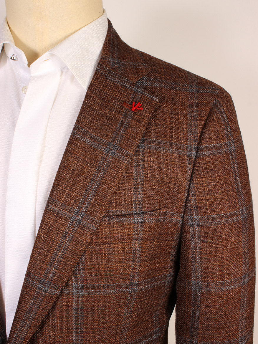 A close-up of a person wearing the Isaia Sanita Flap Pocket Sport Jacket in rust plaid, featuring a red lapel pin over a crisp white dress shirt. Made in Italy.