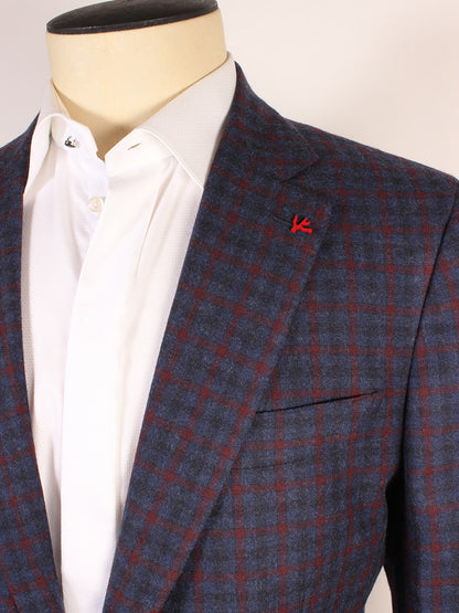 A close-up of a mannequin wearing an Isaia Winter Delain Sport Jacket in Navy & Brick Check over a white dress shirt. A small red pin is attached to the blazer's lapel, highlighting its elegant design made in Italy.