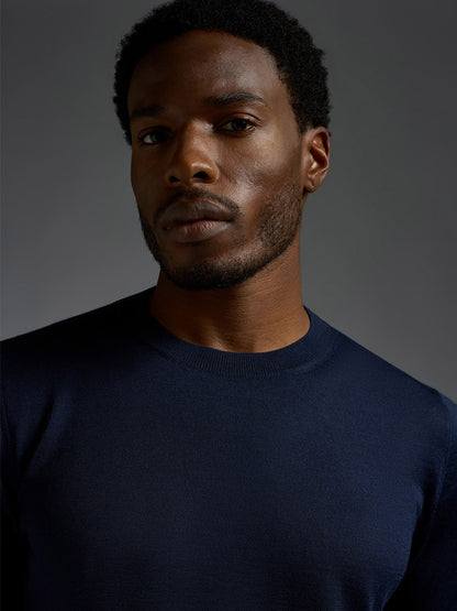A man with short curly hair and a trimmed beard wears an Isaia Wool Cashmere Banded Tee in Navy, looking directly at the camera against a plain dark background.