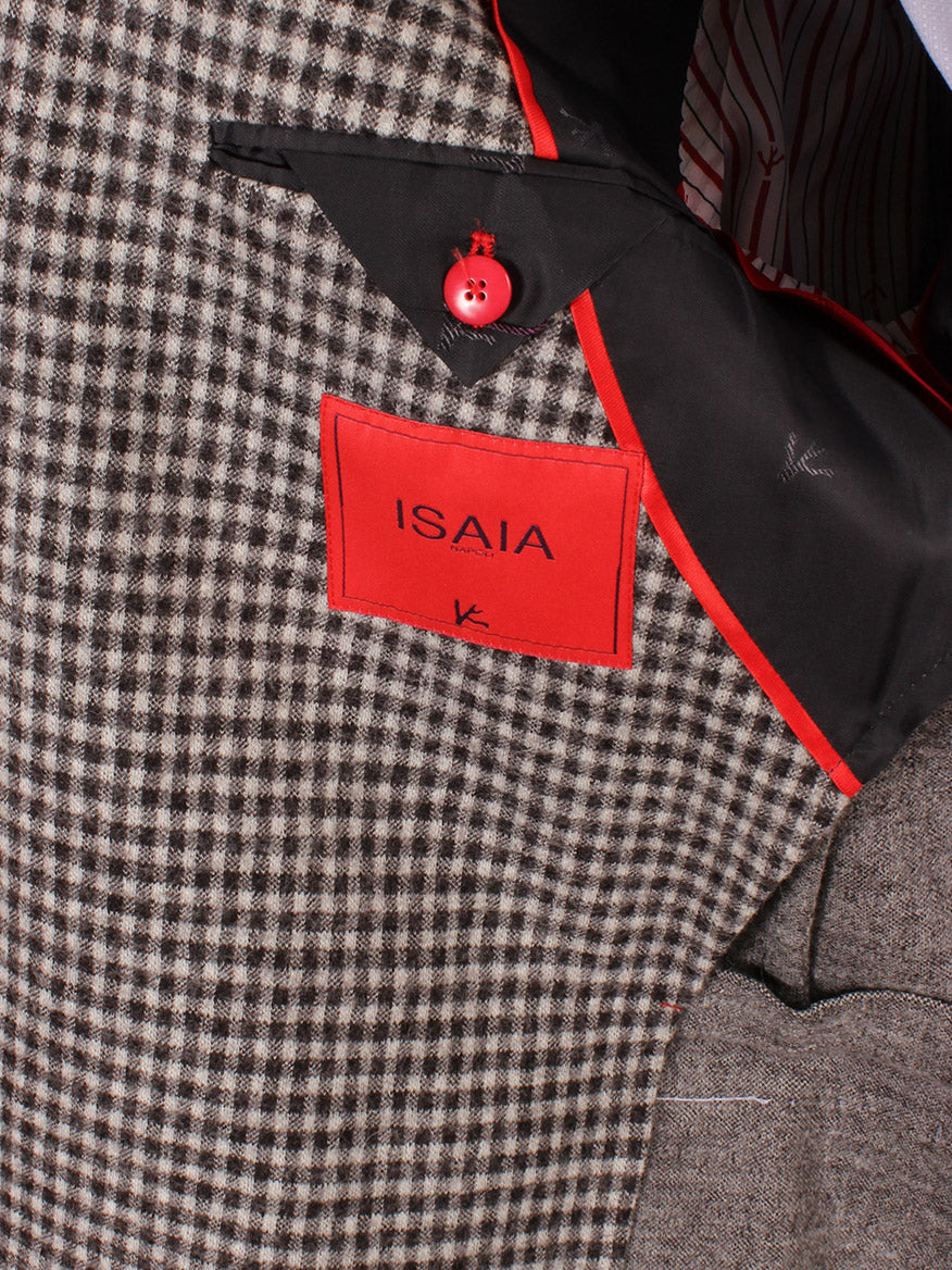 Close-up of a dark brown check Isaia double-face wool sport jacket with a red "isaia" label and coral pin on the notched lapels.