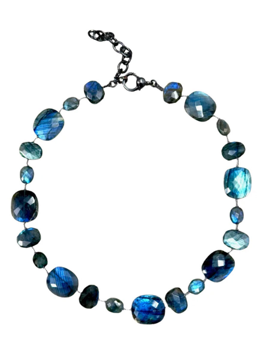 The JMNYC Designs 18" Faceted Labradorite Mix Necklace showcases an array of polished blue gemstones in assorted shapes—including faceted labradorite—strung on a delicate wire and finished with an adjustable sterling silver clasp.