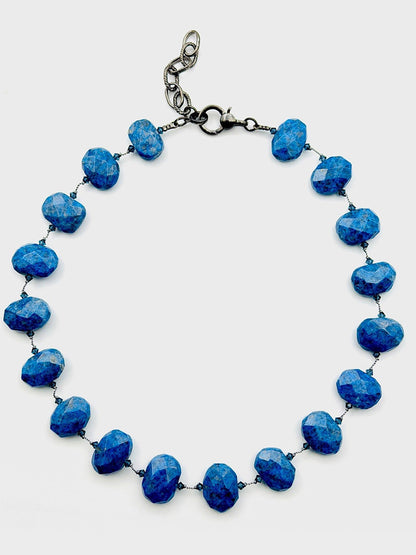 The JMNYC Designs 18" Flat Faceted Denim Lapis Necklace features brilliant flat faceted blue lapis beads, expertly linked with wire and finished with a secure lobster clasp closure. Displayed on a plain white background, this elegant necklace beautifully highlights the lustrous sparkle of each bead.