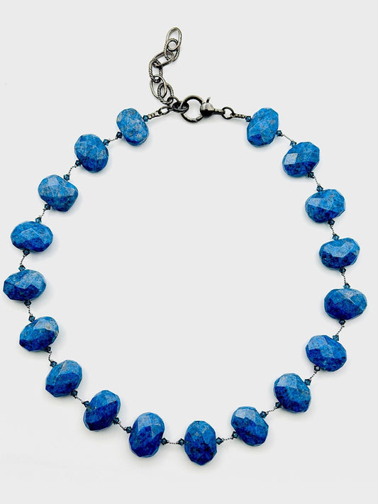 The JMNYC Designs 18" Flat Faceted Denim Lapis Necklace features brilliant flat faceted blue lapis beads, expertly linked with wire and finished with a secure lobster clasp closure. Displayed on a plain white background, this elegant necklace beautifully highlights the lustrous sparkle of each bead.