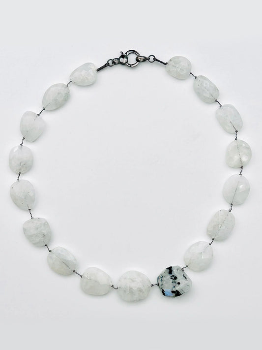 JMNYC Designs 18" Flat Faceted Rainbow Moonstone Necklace, showcasing irregular white stones and a larger faceted moonstone with black speckles, all connected by visible wire and finished with a sterling silver clasp, displayed on a light background.