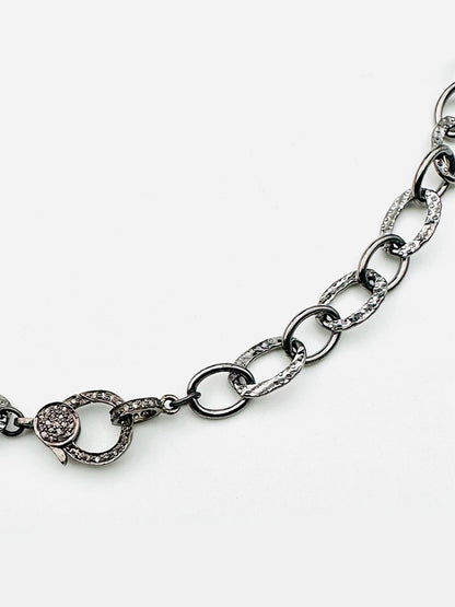 The JMNYC Designs 18" Hammered Oval Rhodium Plated Sterling Silver Chain features a diamond clasp and oval links, with several links and the clasp embellished with small clear crystals.