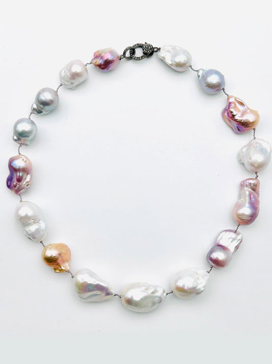 The JMNYC Designs 18" Ombre White/Grey Freshwater Baroque Pearl Necklace features large, irregularly shaped pearls in a gradient of white and grey tones, elegantly finished with a sparkling diamond clasp. This sophisticated piece combines unique colors and textures for a standout look.