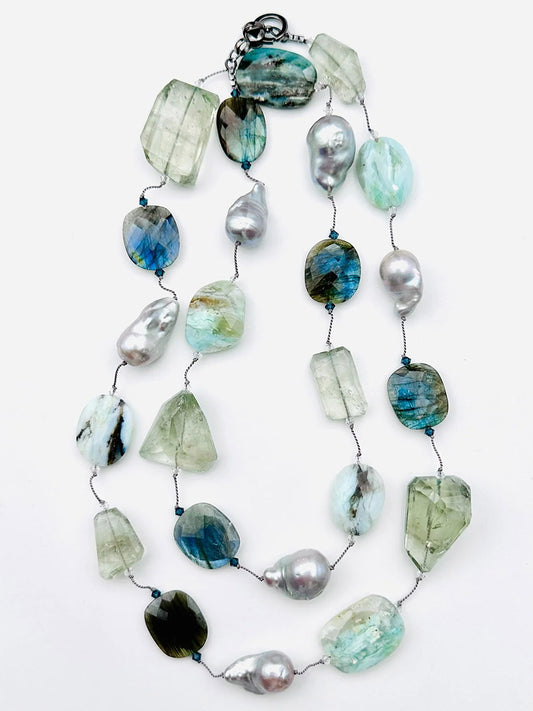 The JMNYC Designs 36" Faceted Opal, Labradorite, Green Amethyst & Grey Pearl Necklace features faceted opal, labradorite, and green amethyst stones alongside grey pearls, all elegantly strung on a thin wire with a metal clasp.