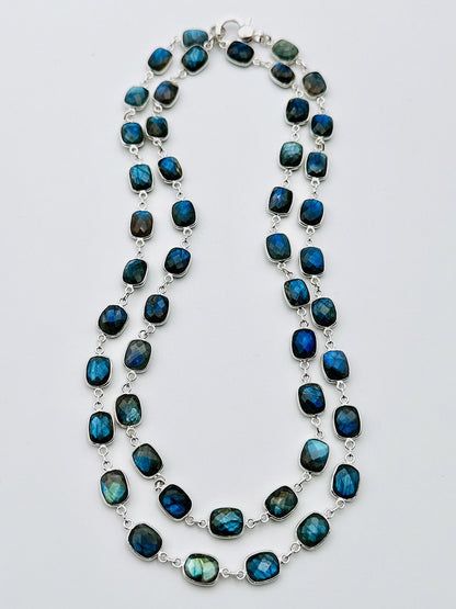 The JMNYC Designs 36" Rectangular Labradorite with Rhodium Bezel and Clasp showcases double strands of mesmerizing blue-green iridescent labradorite stones, each elegantly set in rhodium bezel silver links and displayed on a plain white background.