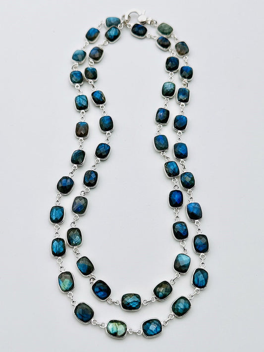 The JMNYC Designs 36" Rectangular Labradorite with Rhodium Bezel and Clasp showcases double strands of mesmerizing blue-green iridescent labradorite stones, each elegantly set in rhodium bezel silver links and displayed on a plain white background.