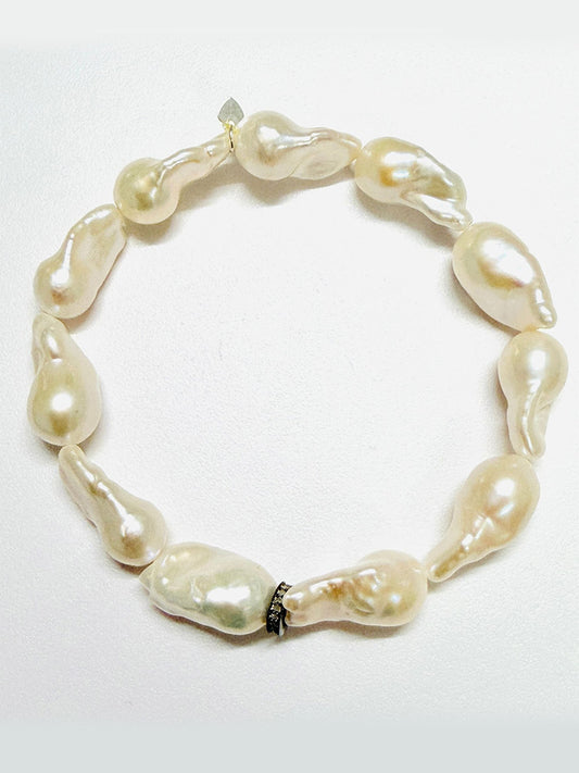 The JMNYC Designs AA Medium White Baroque Pearl with Diamond Rondelle, 7.25" bracelet showcases large, uniquely shaped white baroque pearls, each elegantly separated by a sparkling diamond rondelle and arranged in a graceful circle against a plain white background.