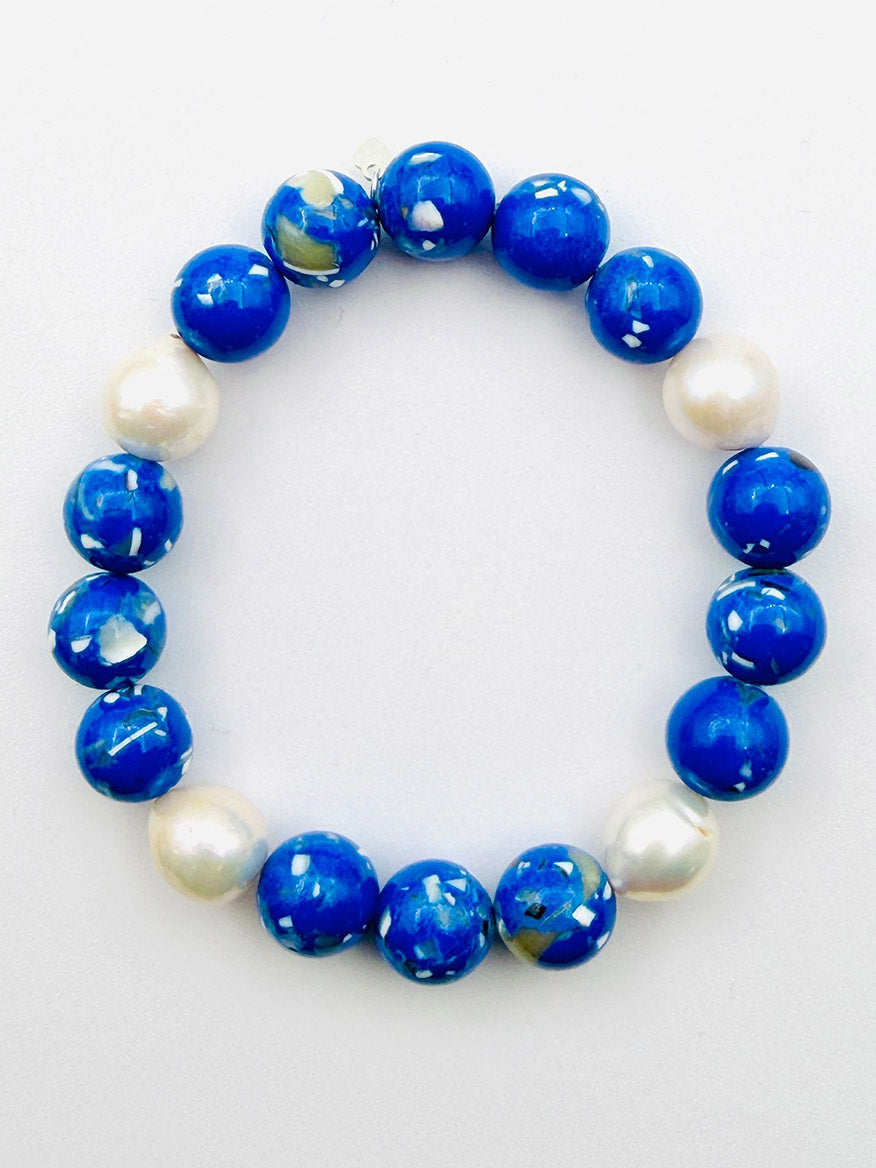 A JMNYC Designs Bright Blue Jasper Ball Bracelet with a Freshwater Baroque Pearl, 7.25", is arranged in a circle on a plain white background.
