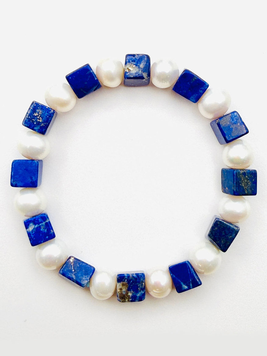 JMNYC Designs Cube Lapis and White Freshwater Pearl Bracelet, 7.35", showcases alternating square blue lapis stones and round freshwater pearls, elegantly arranged in a circle on a plain white background.