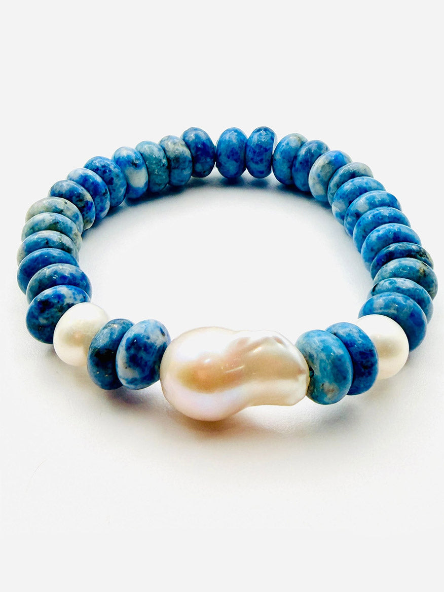 Introducing the JMNYC Designs Denim Lapis and White Freshwater Pearl Bracelet, 7.25"—a limited edition piece showcasing denim lapis blue round stones paired with three luminous white pearls, including one large, uniquely shaped white freshwater pearl, elegantly displayed on a pristine white background.