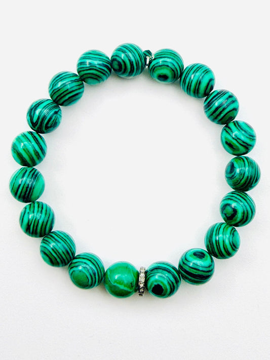 A JMNYC Designs Emerald Green Fordite Ball Bracelet with Diamond Rondelle featuring green and black striped round beads and a small silver accent, styled against a white background and evocative of an emerald green bracelet.