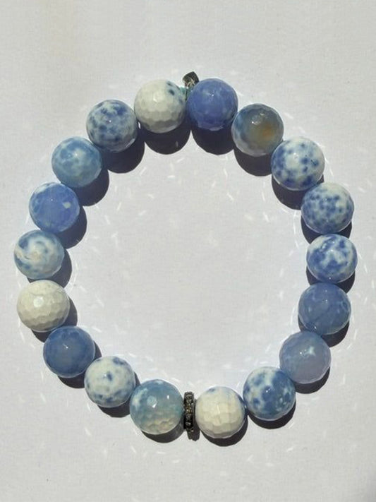 A JMNYC Designs Faceted Periwinkle Agate Ball Bracelet with Diamond Rondelle, 7.25", featuring round, blue and white marbled agate stones and a sparkling diamond-accented rondelle, arranged in a circle on a white background.