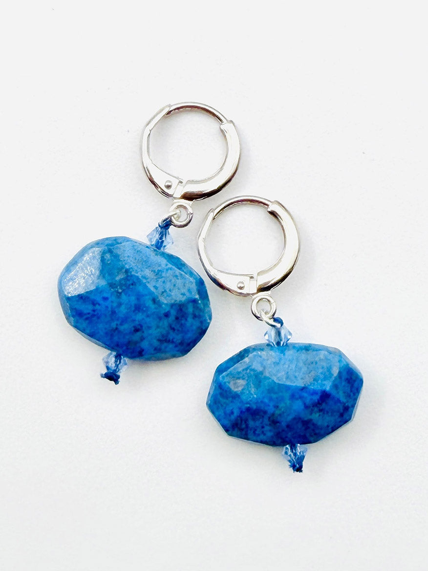 A pair of JMNYC Designs Flat Faceted Denim Lapis Earrings on Sterling Silver Huggie, featuring large faceted denim lapis stone pendants attached with blue thread and displayed on a white background.