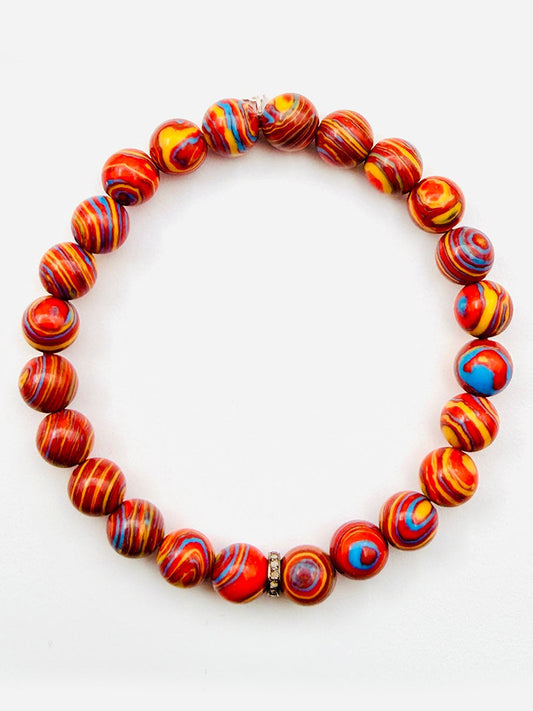 Introducing the JMNYC Designs Graffiti Blue Fordite Ball Bracelet with Diamond Rondelle, 7.25": A vibrant beaded bracelet crafted with round, multicolored red, yellow, and blue marbled Fordite beads—accentuated by a single metallic accent bead and a sparkling Diamond Rondelle. Shown against a white background, this exclusive piece is part of our Limited Edition collection.