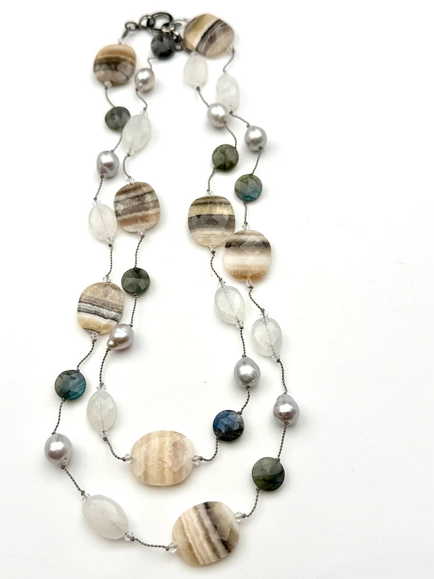 The JMNYC Designs Agate, Labradorite, Moonstone & Pearl Necklace showcases large striped grey agate oval stones, round colorful beads, and delicate small pearls, all connected by a thin metallic chain and presented on a white background.