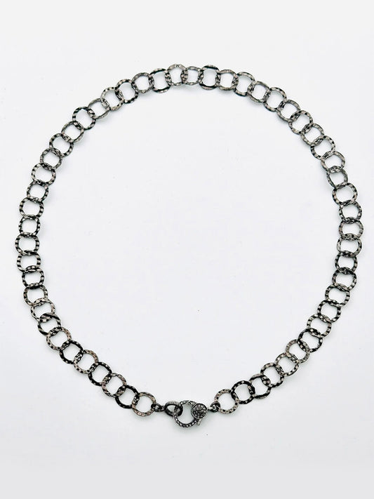 The JMNYC Designs Sterling Silver Rhodium Hammered Round Link Chain Necklace with Diamond Clasp, 18", is displayed in a circular shape on a plain white background.