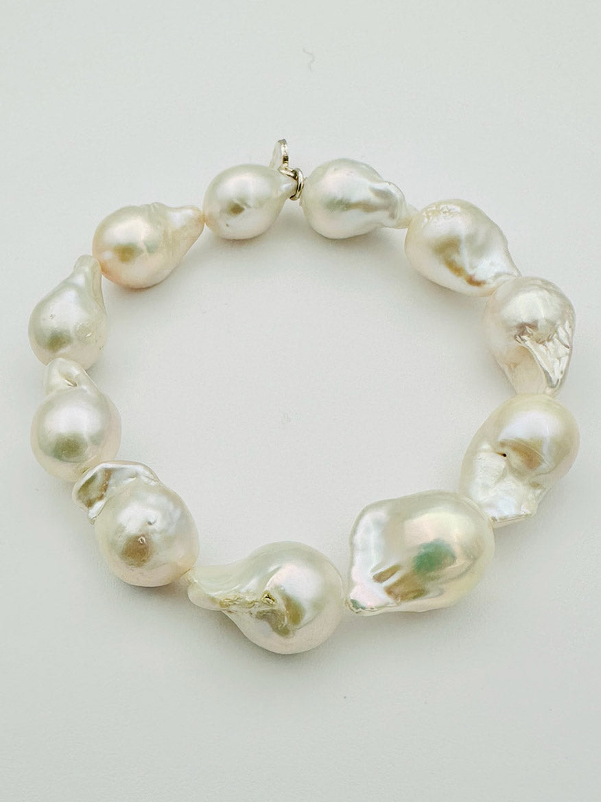 The JMNYC Designs Medium Baroque Pearl Bracelet, crafted with large, irregularly shaped white baroque pearls and finished with gold-filled accents, is displayed arranged in a circle on a plain light background.