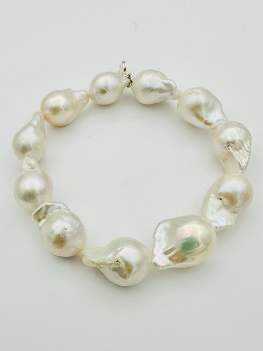The JMNYC Designs Medium Baroque Pearl Bracelet, crafted with large, irregularly shaped white baroque pearls and finished with gold-filled accents, is displayed arranged in a circle on a plain light background.