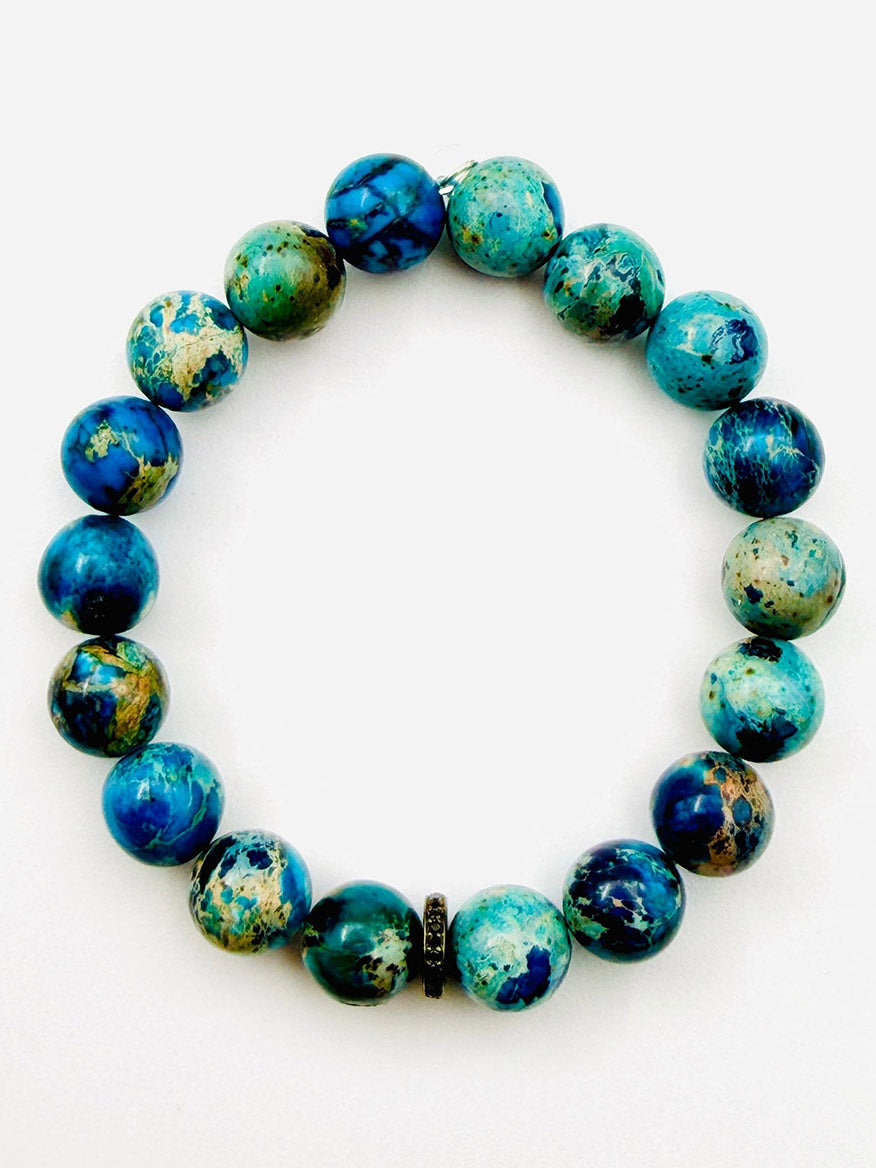 Introducing the JMNYC Designs Natural Azurite Chrysocolla Ball Bracelet with Black Spinel Rondelle, 7.25"—a limited edition jewelry piece featuring round blue and green marbled azurite chrysocolla stones accented by a shimmering black spinel rondelle, all elegantly arranged in a circle on a white background.