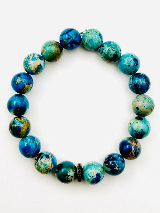 Introducing the JMNYC Designs Natural Azurite Chrysocolla Ball Bracelet with Black Spinel Rondelle, 7.25"—a limited edition jewelry piece featuring round blue and green marbled azurite chrysocolla stones accented by a shimmering black spinel rondelle, all elegantly arranged in a circle on a white background.