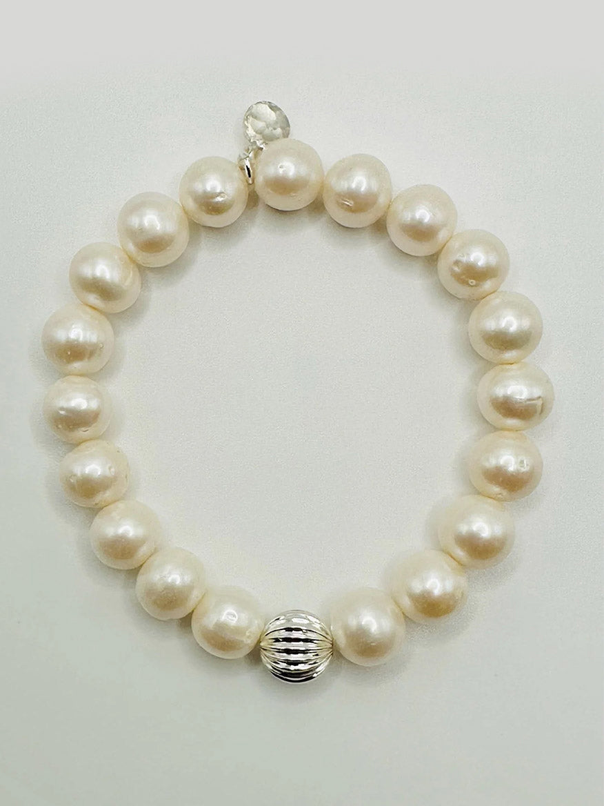 The JMNYC Designs 10mm Round Freshwater Pearl Bracelet features round pearls, a ribbed sterling silver ball accent, and a small circular clasp, shown on a light background.