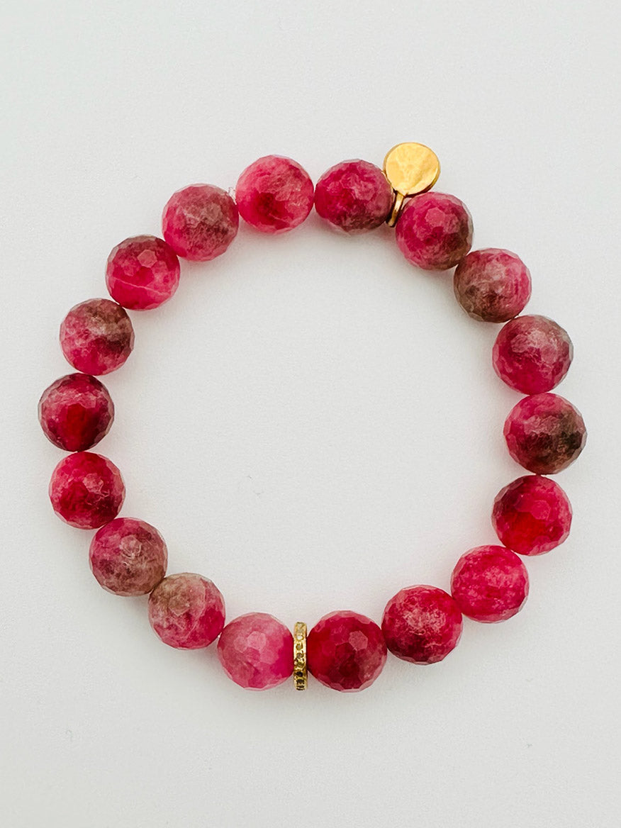 The JMNYC Designs Pink Tourmaline Bracelet with Gold Diamond Rondelle, 7.25", showcases round, faceted pink and maroon tourmaline stones accented by a small gold disk and a single Gold Diamond Rondelle spacer bead, elegantly displayed on a white background. The bracelet measures 7.25 inches for a comfortable fit.