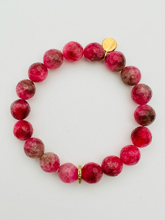 The JMNYC Designs Pink Tourmaline Bracelet with Gold Diamond Rondelle, 7.25", showcases round, faceted pink and maroon tourmaline stones accented by a small gold disk and a single Gold Diamond Rondelle spacer bead, elegantly displayed on a white background. The bracelet measures 7.25 inches for a comfortable fit.