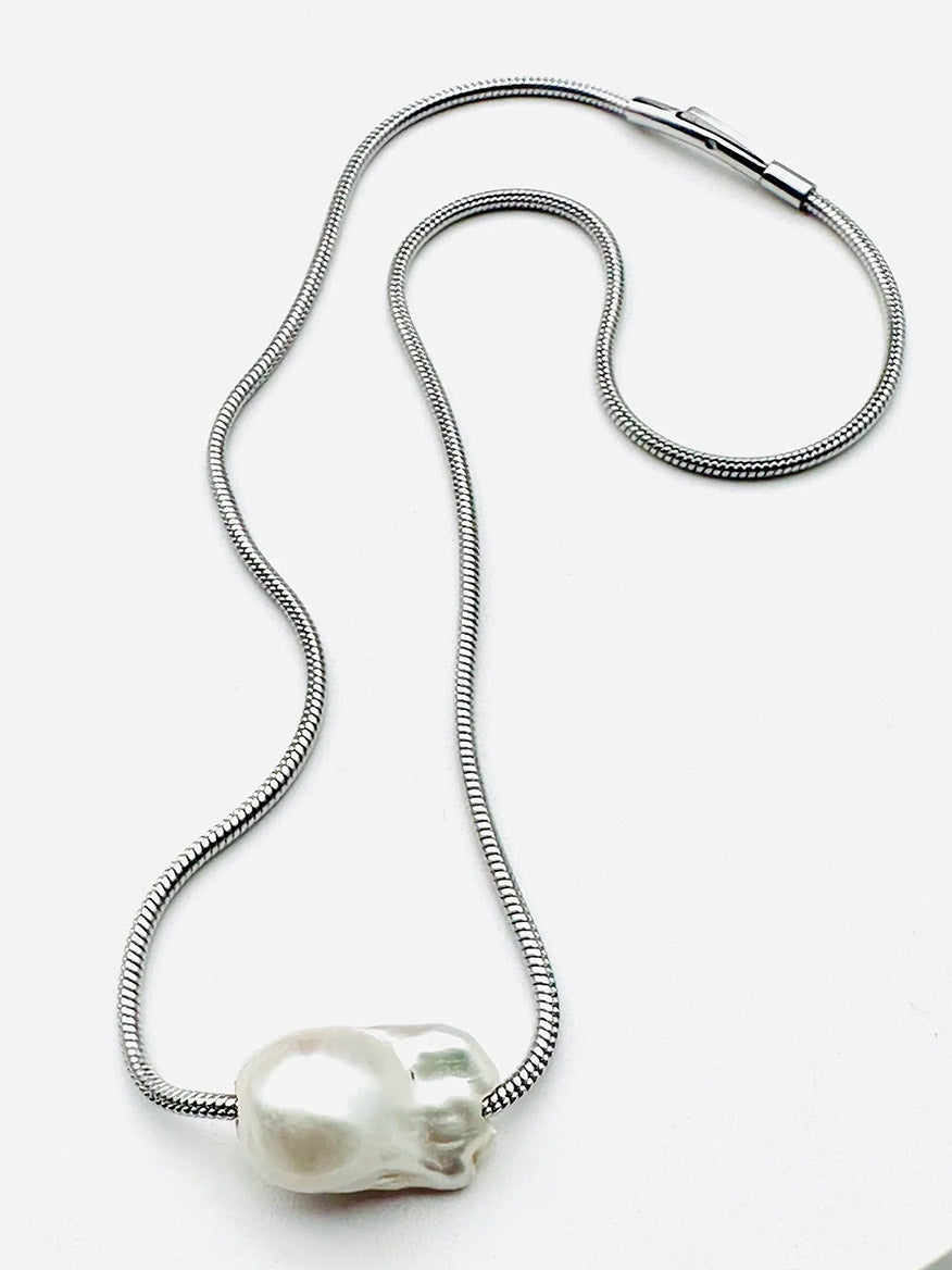 The JMNYC Designs Removable White Baroque Freshwater Pearl Silver Steel Chain features a sleek snake chain in silver and a large, irregularly shaped Baroque Freshwater Pearl pendant. Displayed on a white background, this elegant necklace offers versatility with its removable pearl design.