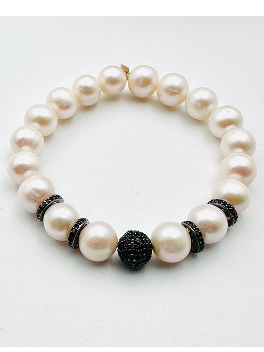 The JMNYC Designs Round White Freshwater Pearl Bracelet with Black Spinel & Rondelles features large, round white pearls accented by small black spinel rondelles as spacers and a single, larger black bead centerpiece, displayed on a plain white background.