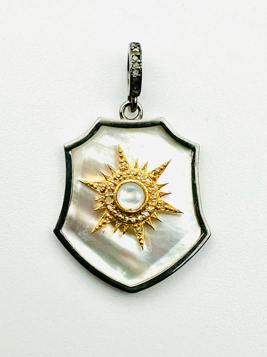 The JMNYC Designs Mother Of Pearl Sun Shield features a mother-of-pearl backdrop, gold sunburst motif, central white gemstone, and a hanging loop, all set in a Diamond Two Tone Frame of Gold Vermeil & Sterling Silver.