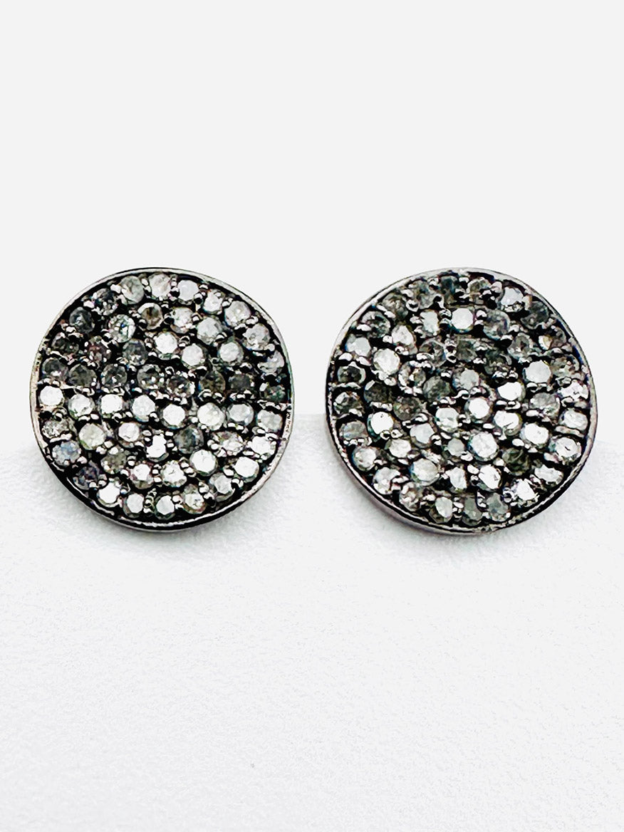The JMNYC Designs Pave Diamond Wavy Disk Earrings feature round sterling silver studs adorned with pave-set white and dark stones in a swirling, wavy disk pattern, showcased against a plain white background.